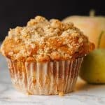 Close up of an Apple muffin with crumb topping with apples in the background