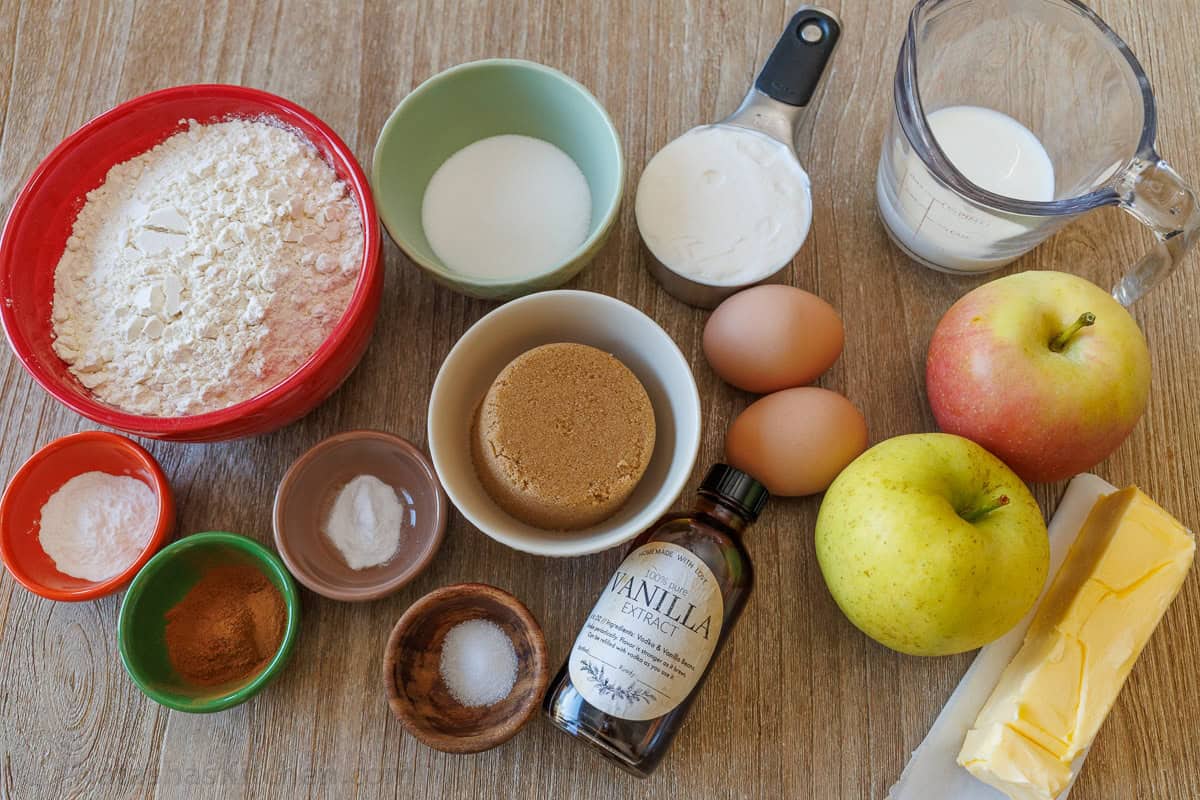 Ingredients for best apple muffin recipe with flour, baking powder, baking soda, salt, ground cinnamon, brown sugar, sugar, butter, eggs, vanilla, sour cream, milk, and apples