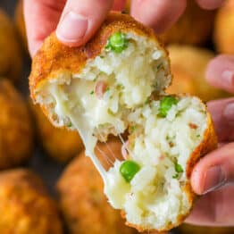 Arancini rice ball open to a cheesy center