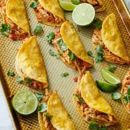 Baked Chicken Tacos on a cooking sheet with lime slices