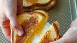 Two oven-toasted sandwiches on a cookie sheet cut in half