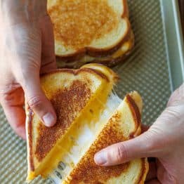 Two oven-toasted sandwiches on a cookie sheet cut in half