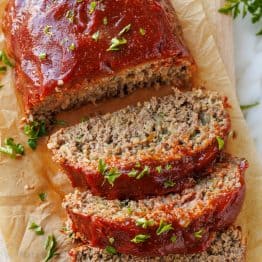 Best Meatloaf Recipe sliced on a cutting board and garnished with parsley