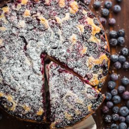 Lemon Blueberry Cake dusted with powdered sugar and slice cut out