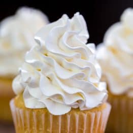 White Vanilla buttercream frosting piped onto a yellow cake cupcake