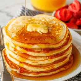 Buttermilk Pancakes stacked on a plate served with maple syrup