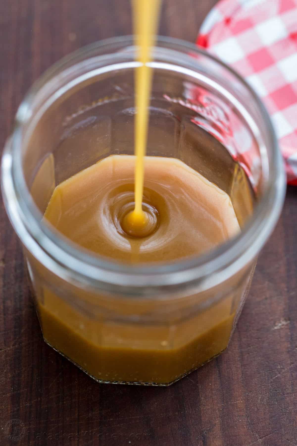 drizzling ice cream topping into a mason jar for storage