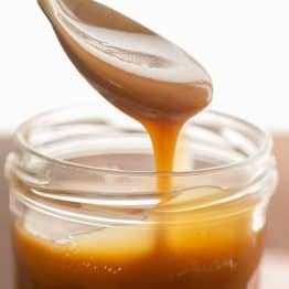 Scooping homemade butterscotch sauce using a spoon