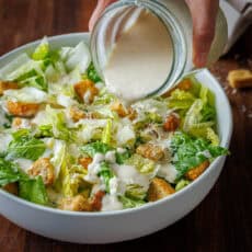Creamy caesar dressing poured over romaine and croutons