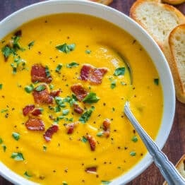Creamy Carrot Soup in white bowl garnished with bacon