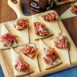 Manchego Cheese Bites on a cutting board with fig spread in the background