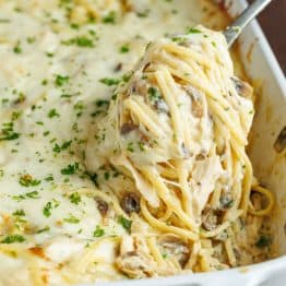 A fork scooping chicken tetrazzini recipe out of a serving dish