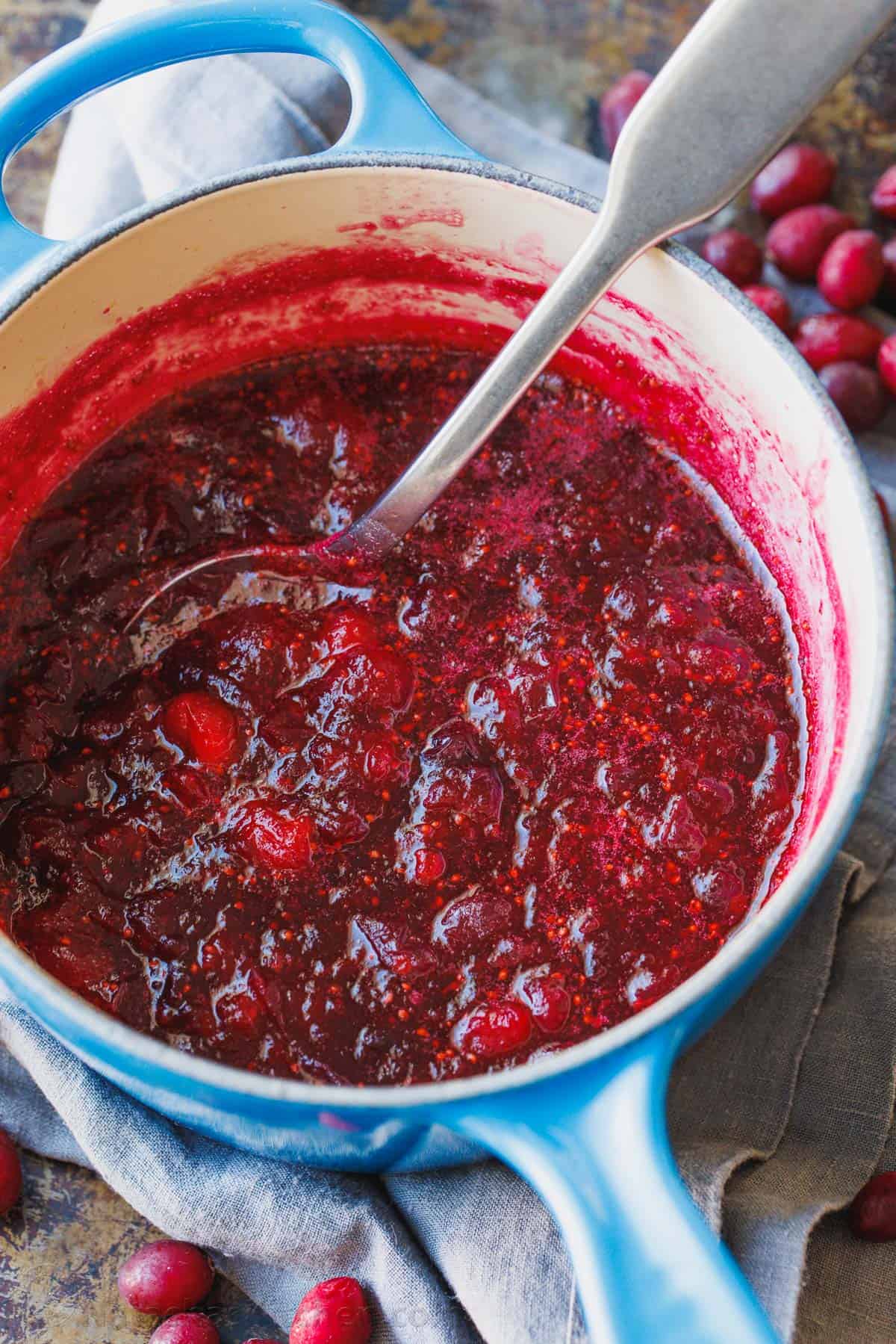 Cranberries simmering in a pot with sugar and water.