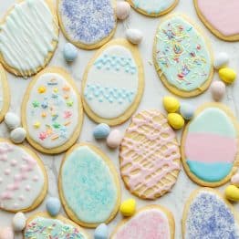 Easter Sugar Cookies with pastel colors, sprinkles and egg-shaped candies on marble countertop