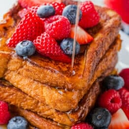 Stack of french toast served with berries and maple syrup