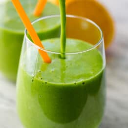Green smoothie recipe poured into a cup with a straw