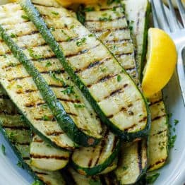 grilled zucchini recipe on a plate with lemon slices and a fork