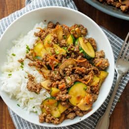 Easy Ground beef stir fry in a white bowl with a fork and tea towel