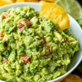Guacamole served in a white bowl with a tortilla chip