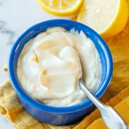 Creamy Homemade Mayonnaise in a blue ramekin with a spoon.