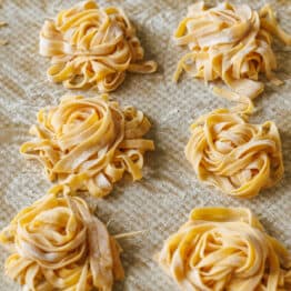 homemade pasta dough in nests on a baking sheet