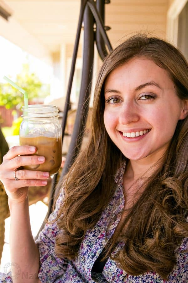 Natasha holding an iced coffee with condensed milk in a mason jar with a straw 