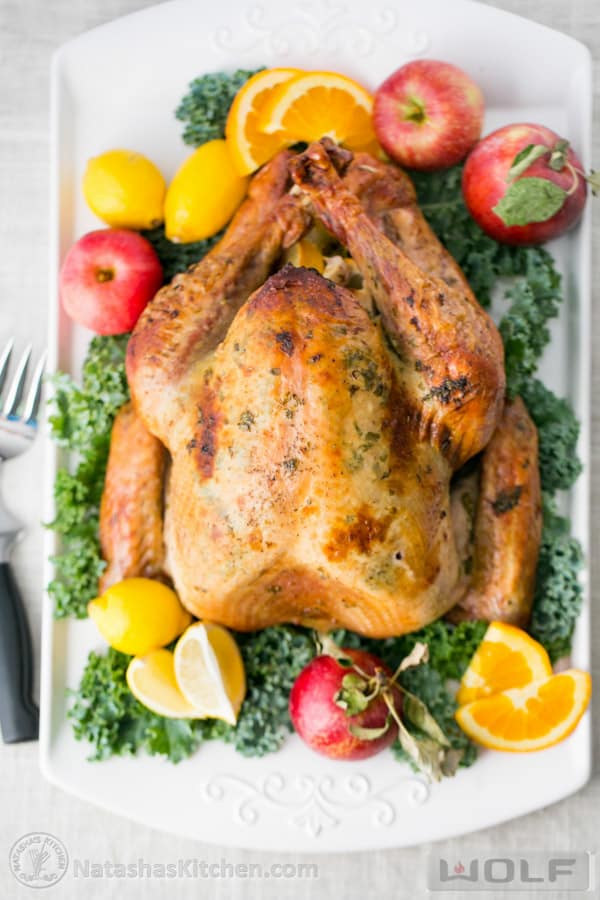 Juicy Roast Turkey on a serving platter decorated with kale and fruit