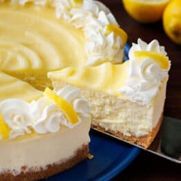 Lemon cheese cake topped with lemon curd and piped whipped cream with one slice being served
