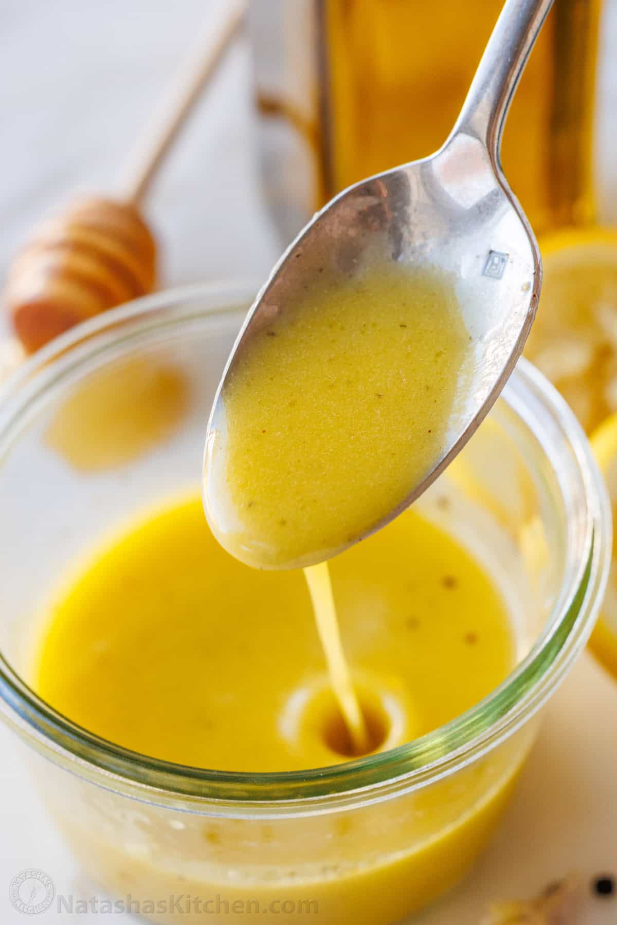 a spoon drizzling Lemon vinaigrette dressing into a mason jar