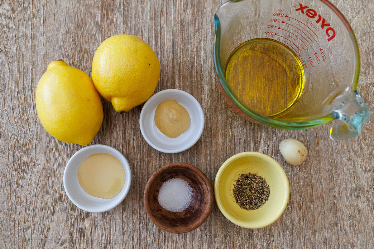 ingredients for dressing a salad including dijon mustard, salt, pepper, garlic, honey, and olive oil