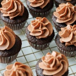 Mini Chocolate Cupcakes topped with piped Chocolate Buttercream frosting on a metal cooling rack