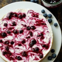 beautiful no-bake Blueberry Cheesecake on a white plate with blueberry topping