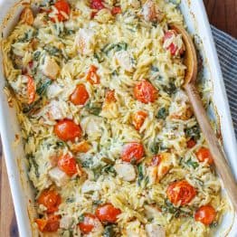 Creamy chicken pasta casserole with cherry tomatoes in a white casserole dish
