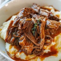 classic pot roast recipe served over mashed potatoes in a white bowl