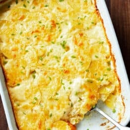 Golden baked au gratin potatoes in a rectangular baking dish with a scoop missing.