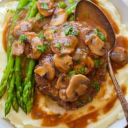 Salisbury steak dinner with mashed potatoes, asparagus and mushrooms