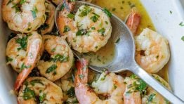 Shrimp scampi recipe in a white dish with butter garlic sauce and parsley garnish