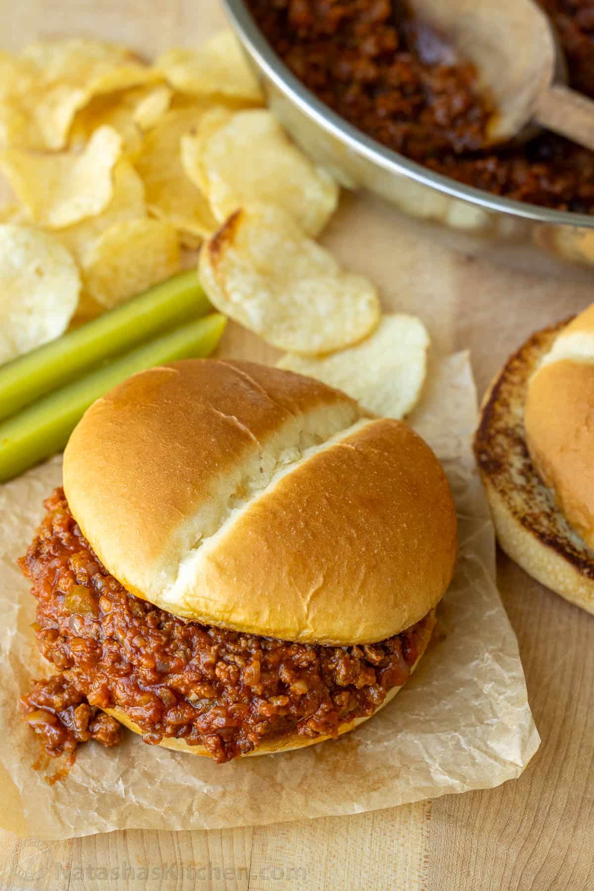 Sloppy Joe served in a toasted bun with potato chips and pickle spears