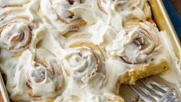 Sourdough cinnamon rolls frosted in a baking pan with 1 cinnamon roll removed