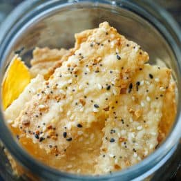 Sourdough Discard Crackers seasoned with salt and sesame seeds and baked to golden perfection in a glass jar for storage.