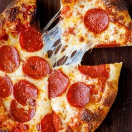 A slice pulled from a whole pizza using homemade sourdough pizza dough