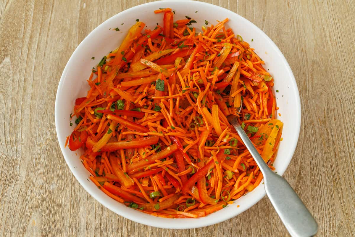 mixing shredded vegetables in a bowl with dressing