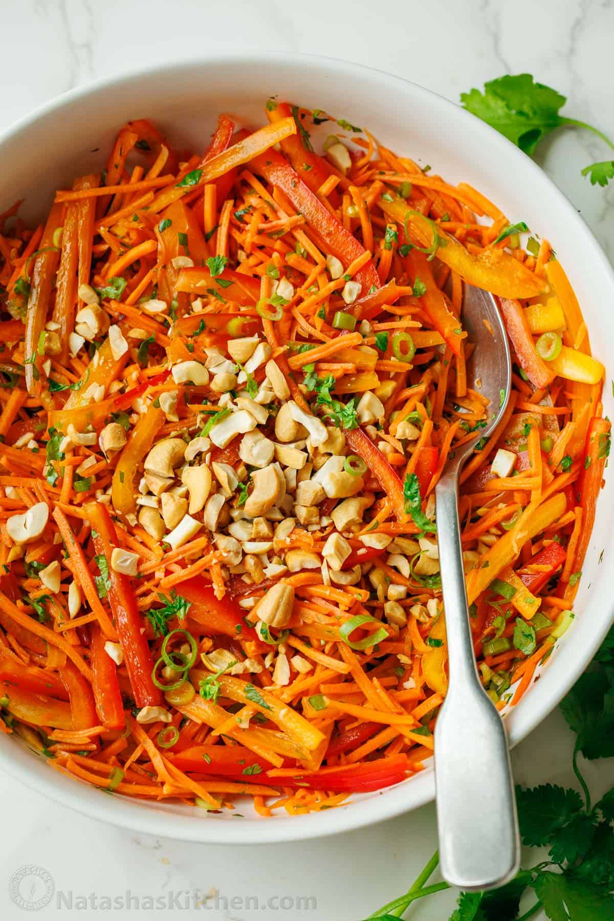 Cashews on top of a Spicy Korean Carrot Salad with peppers and spicy dressing