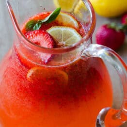 Strawberry Lemonade in a pitcher garnished with strawberries and lemon