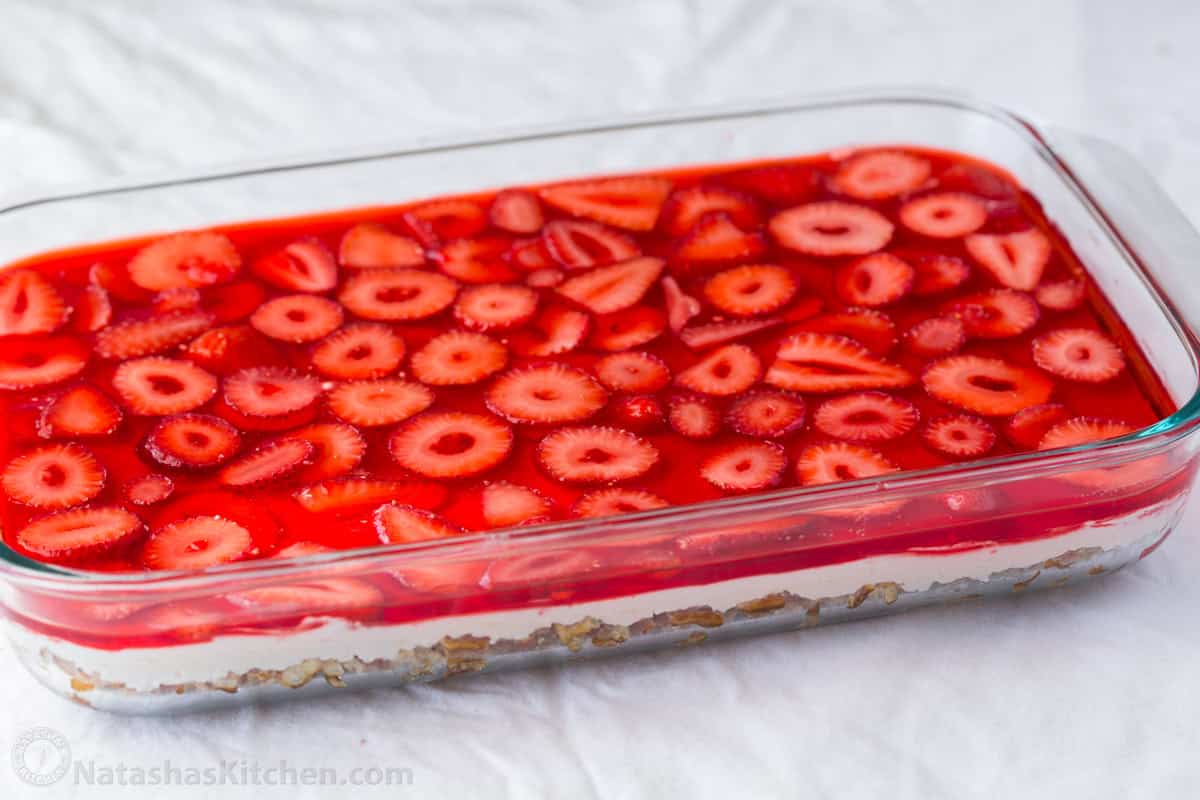 Strawberry Pretzel salad in a clear casserole dish with strawberry jello layer on top