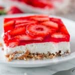 Strawberry Pretzel Salad on a white plate with sliced strawberries