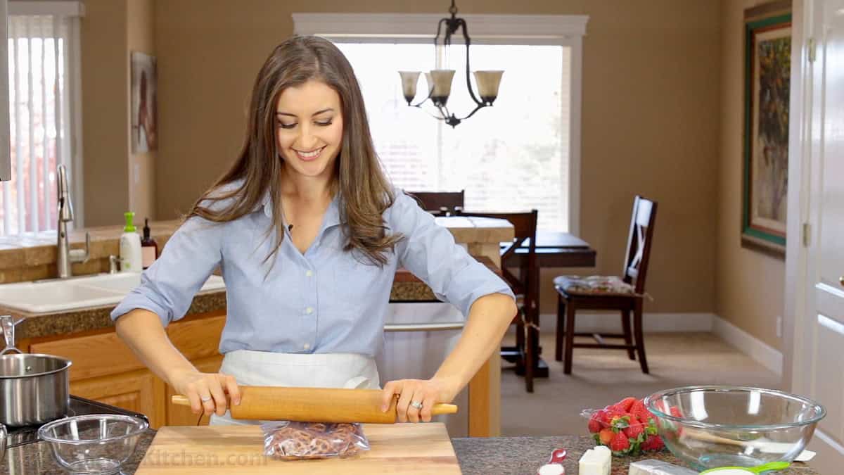 Natasha showing how to crush pretzels for Strawberry Pretzel Salad using a rolling pin
