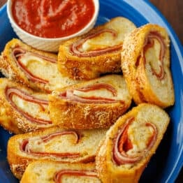 Stromboli sliced into pinwheels on a plate with marinara dipping sauce in a ramekin