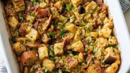 Turkey stuffing recipe in a white casserole dish with parsley garnish chopped sourdough bread