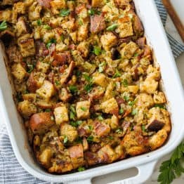 Turkey stuffing recipe in a white casserole dish with parsley garnish chopped sourdough bread